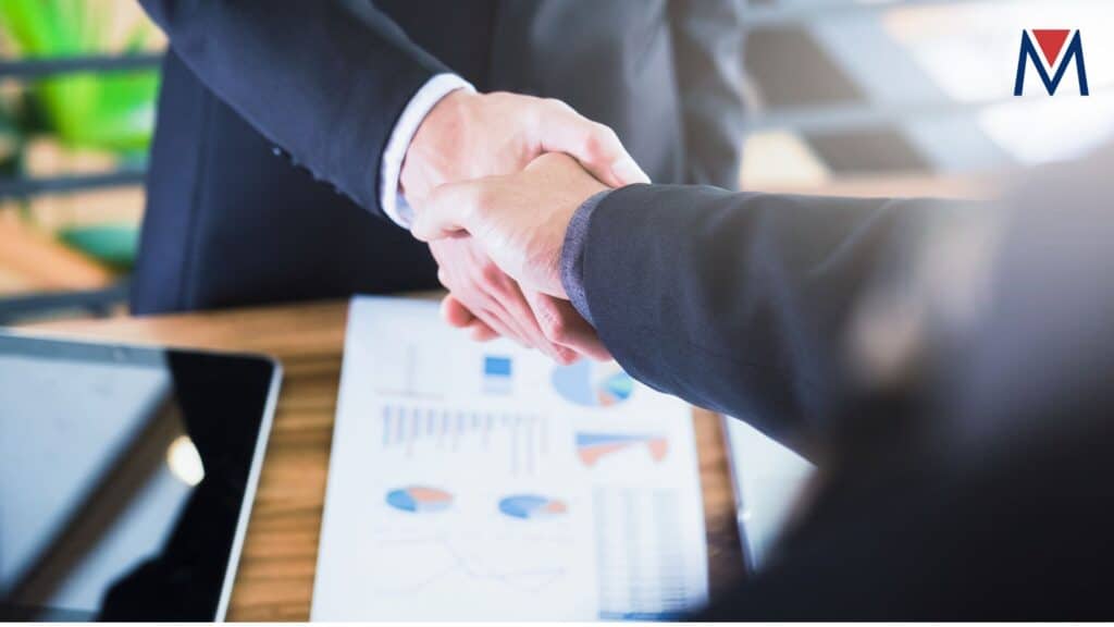 Two businessmen shaking hands over a dashboard displaying FMCG trends